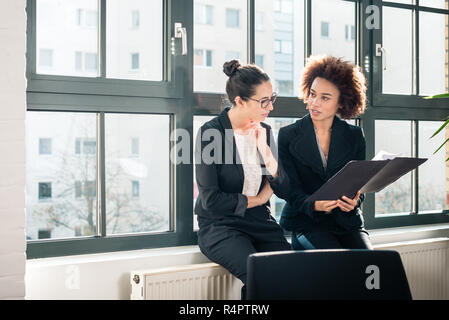 Two young colleagues reviewing business reports during break Stock Photo