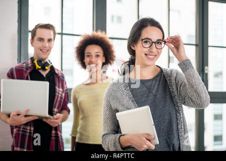 Portrait of young man smiling while holding a laptop at work Stock Photo