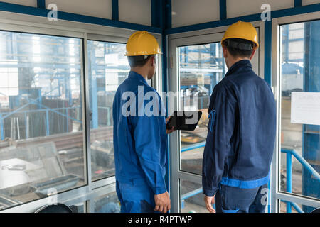 Two workers wearing hard hats while using a tablet PC Stock Photo