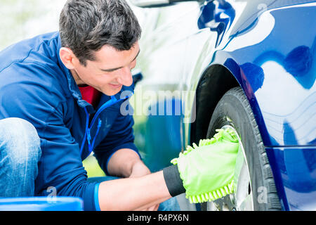 Worker using microfiber car wash mitt for cleaning rim Stock Photo