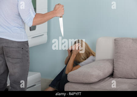 Man Holding Knife In Front Of A Frighten Woman Stock Photo