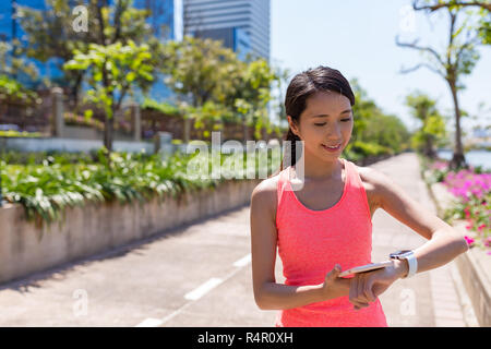 Sport Woman running with smart watch in green park Stock Photo
