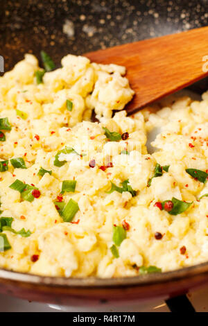 Scrambled eggs with onion on black pan Stock Photo