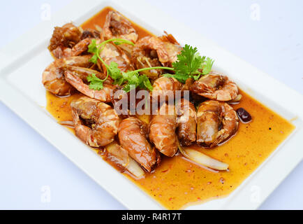 Sauteed shrimp with sauce and herbs on white platter Stock Photo