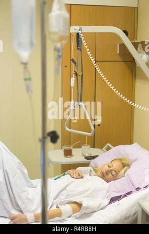 Bedridden female patient recovering after surgery in hospital care. Stock Photo