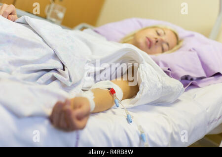 Bedridden female patient recovering after surgery in hospital care. Stock Photo