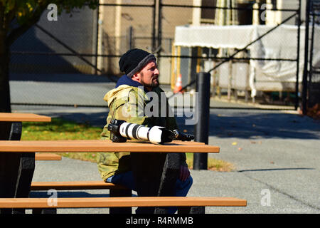 Photographer sitting on bench with a camera the has zoom lens Stock Photo