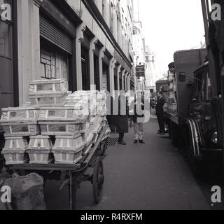 1960s, historical, men on a pavement talking by a truck parked by the kerb and by a cart stacked with crates, at covent garden, london, the site of the British wholelsale fresh fruit and flower market in this era. Stock Photo