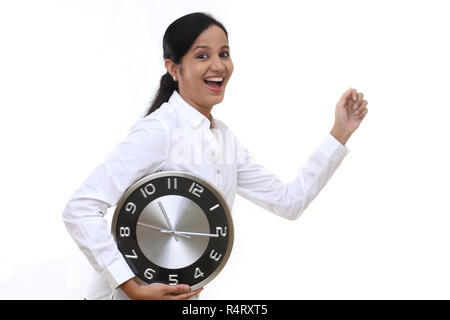 Business woman running and holding a clock against white background Stock Photo