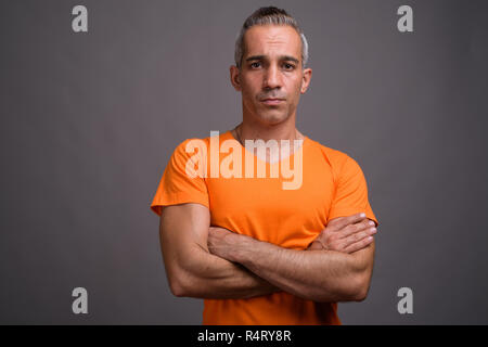 Handsome Persian man with gray hair wearing orange t-shirt Stock Photo