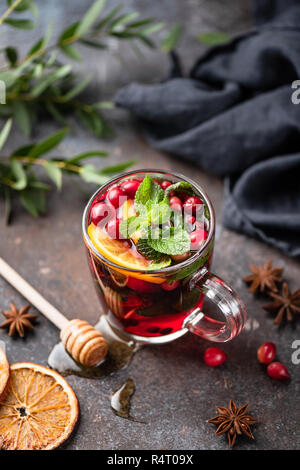 Hot spicy cranberry mulled wine or cranberry tea in glass cup decorated with orange peel and mint leaf Stock Photo