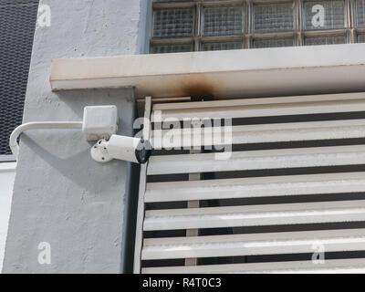 Modern CCTV camera on a wall. A blurred night cityscape background. Concept of surveillance and monitoring. Stock Photo