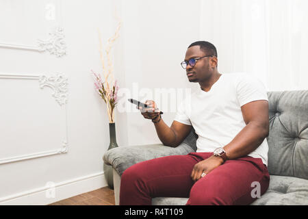 Young African American man watching TV at home. Stock Photo