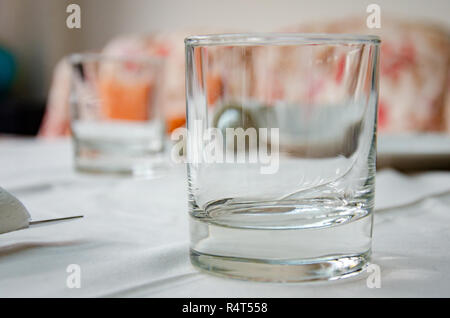 Empty tumbler drinking glasses on a table coverd with a white tablecloth Stock Photo