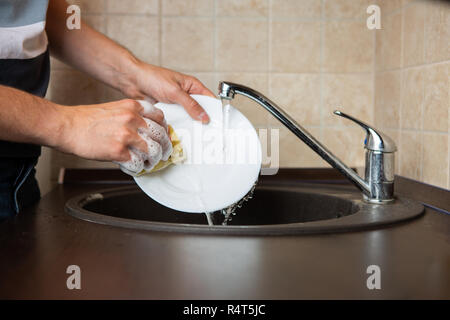 Photo of side of man's hands washing transparent mug in sink Stock Photo