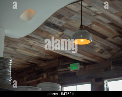 Wooden roof of trendy restaurant with hanging lights and stack of ceramic plates Stock Photo
