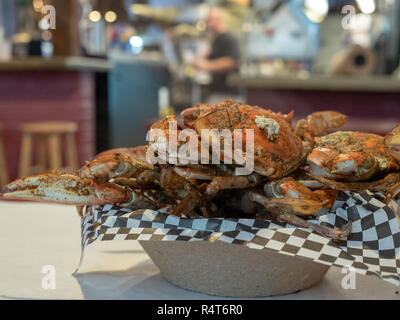 Steamed Chesapeake Bay blue crabs covered in seasoning sitting in paper bowl on paper covered table cloth Stock Photo