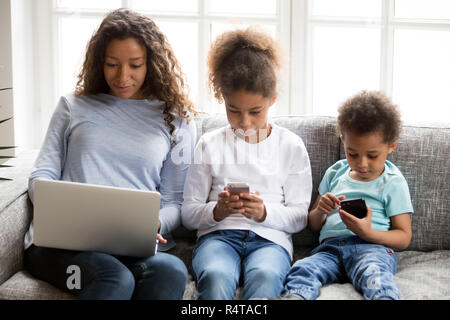 African American family using devices, ignoring each other Stock Photo