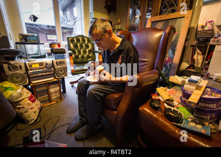 The needy and physically disabled Brian Glover, 59, smokes with friends in his apartment in a Nottingham hostel. He is a needy at Foodbank at Hope House in the Beeston United Reformed Church Nottingham. Stock Photo