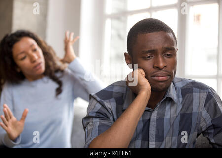 Quarrelling African American couple sitting on couch in living r Stock Photo