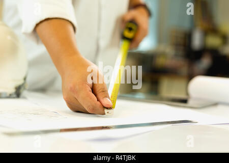 Architecture hand measuring blueprint with tape masure on working table. Stock Photo