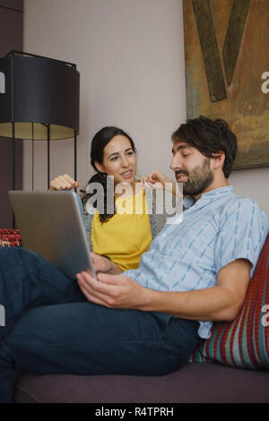 Couple using digital tablet on living room sofa Stock Photo