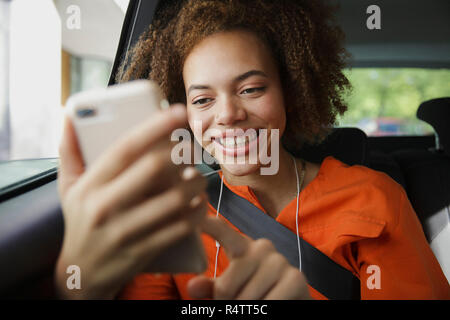 Smiling young woman using smart phone in car Stock Photo