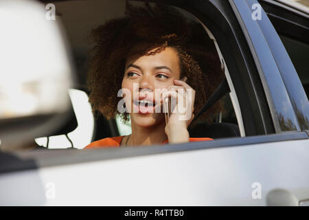 Young woman talking on smart phone and driving car Stock Photo
