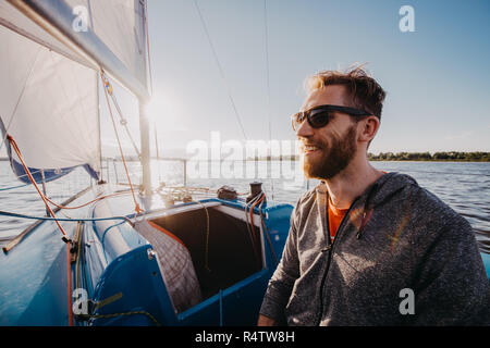 Successful young bearded man sailing portrait at sunrise on boat Stock Photo