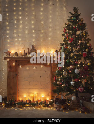 Beautiful Christmas setting, fireplace with wooden mantelpiece fire surround, lit up decorated Christmas tree with baubles and ornaments, stars, Chris Stock Photo