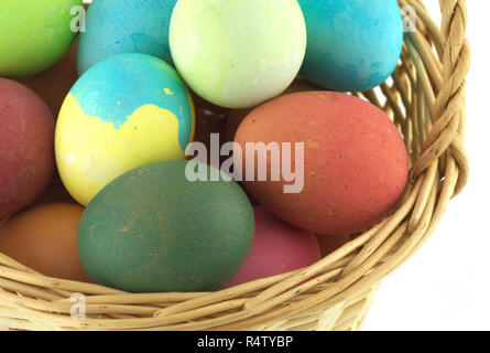 Colorful Easter eggs inside straw wicker brown basket isolate on white closeup Stock Photo