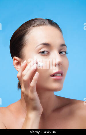 young woman applies moisturizer on her face Stock Photo