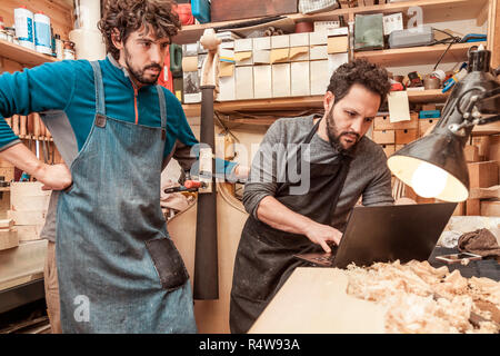 two craftsmen violinmakers checking data and measures for a new violin with computer Stock Photo