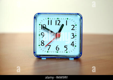 Table alarm clock square shape showing one o'clock on a table front view closeup Stock Photo