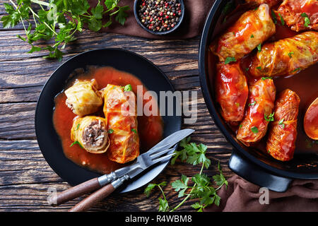 cabbage rolls stuffed with ground beef and rice, cooked to perfection with a tangy tomato sauce in a dutch oven and served on a plate with cutlery, vi Stock Photo