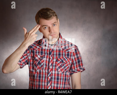 Young man shows headshot with his fingers. Stress or depression concept. Stock Photo