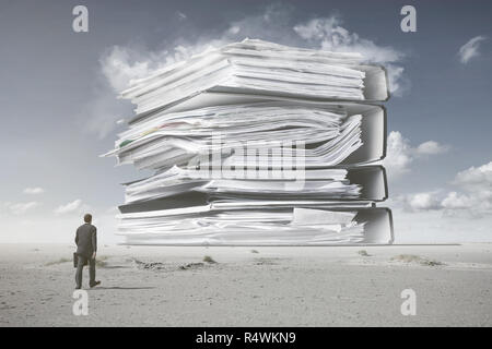 A businessman is walking towards a surreal mountain of paperwork Stock Photo