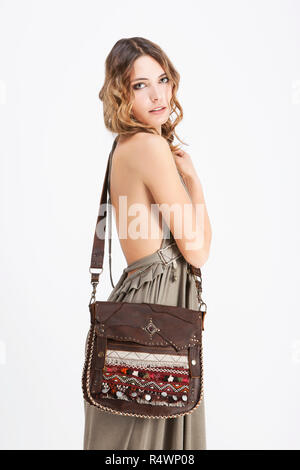 Portrait of a young woman wearing a handbag and a beige dress Stock Photo