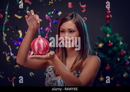 Happy beautiful young woman holding red Christmas baubles. Selective focus. Stock Photo