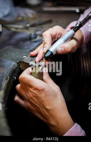 Jeweler polishes a gold ring on an old workbench in an authentic jewelry workshop Stock Photo