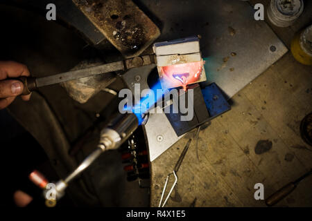 Jeweler pouring with flame melted silver or gold in metal form at jeweler's workshop Stock Photo