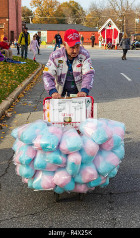 LINCOLNTON, NC, USA-11/25/18: Elderly man pushing a cart filled with cotton candy and candied apples. Stock Photo