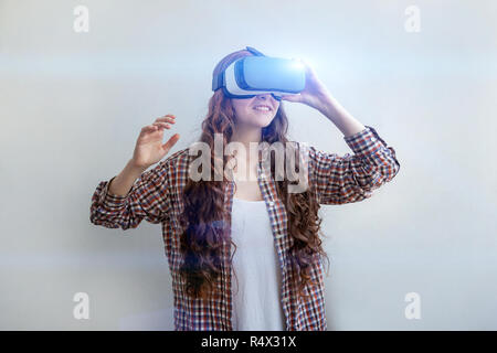 Smile young woman wearing using virtual reality VR glasses helmet headset on white background. Smartphone using with virtual reality goggles. Technology, simulation, hi-tech, videogame concept Stock Photo