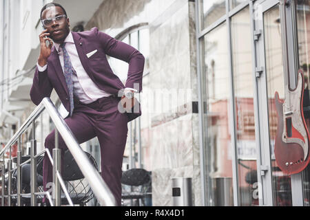Portrait of a young and handsome African American businessman talking in a suit over the phone. Preparing for a business meeting. Stock Photo