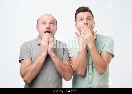 Two mature men of different generation have uexpected gaze up, can not believe in shocking rumors Stock Photo