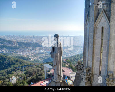 A saint sculpture on the top of the roof of the the Expiatory Church of the Sacred Heart of Jesus, watching a Barcelona landscape, Spain Stock Photo