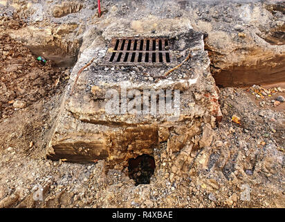 Sewer hole with cover in middle of square under reconstruction.  Semi cross section of sewer or drain grate under road. Stock Photo