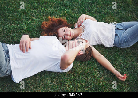 Romantic couple of young people lying on grass in park. They look happy. View from above. Stock Photo