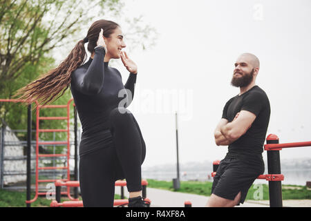 Young man and woman perform exercises and stretch marks before doing sports Stock Photo