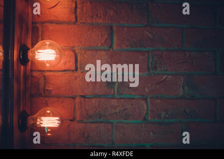 Decorative antique edison style light tungsten bulbs against brick wall background. Stock Photo